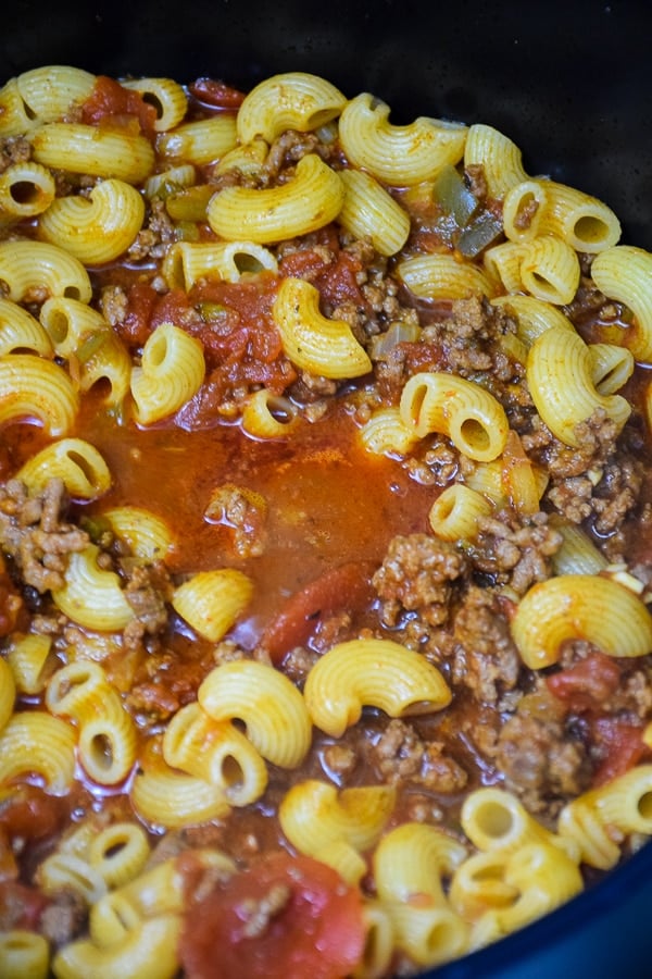 Cooked elbow macaroni in a tomato beef based sauce in a stock pot.