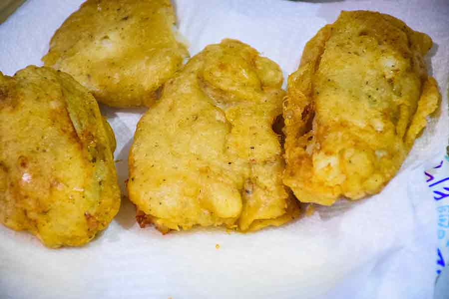 Beer Battered Fish draining on paper towel lined plate.