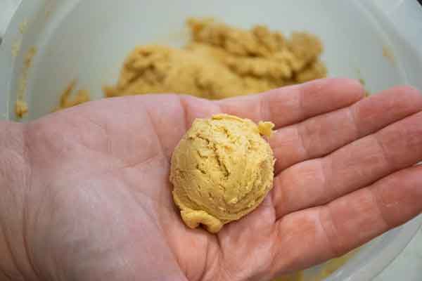 A ball of peanut butter cookie dough in the palm of a hand.