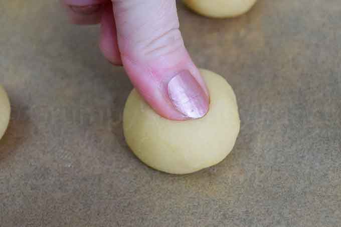 a thumb pressing a dent in the center of the dough