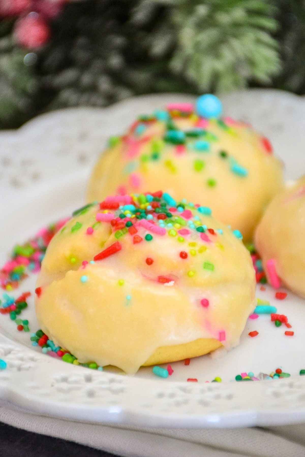 Italian Cookies decorated with pink and blue sprinkles on a white plate.