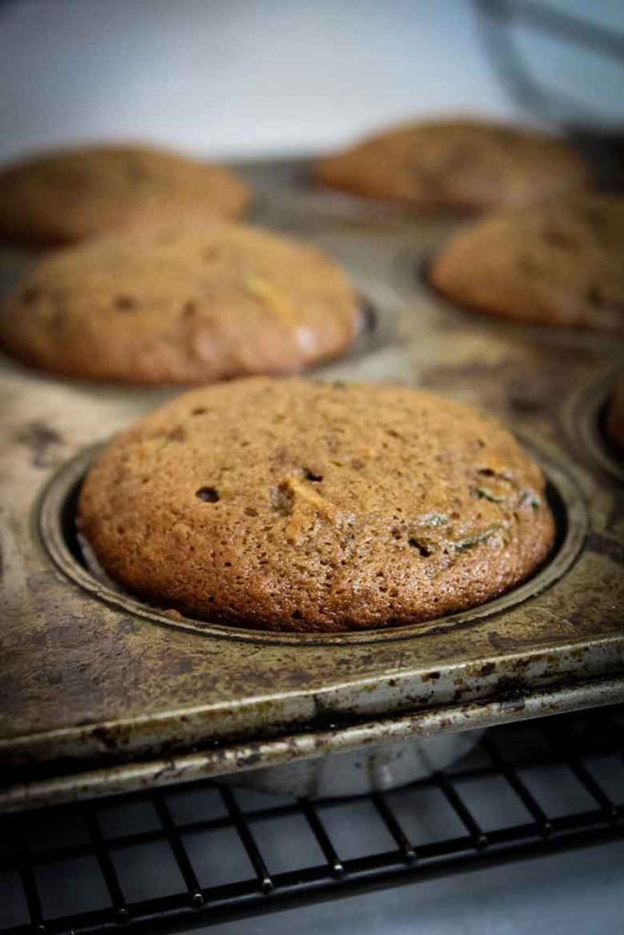 muffin tin with baked chocolate banana zucchini muffins cooling on rack