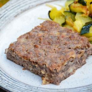 A slice of special K cottage cheese loaf on a plate with a side of sauteed zucchini.