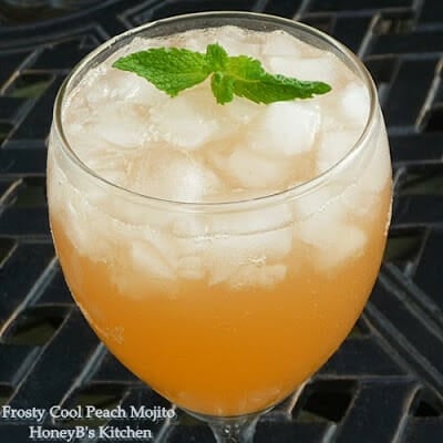 Up close image of peach mojito in a clear glass garnished with mint.