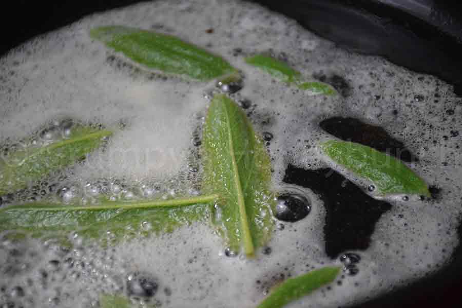 sage leaves frying in butter in a cast iron skillet