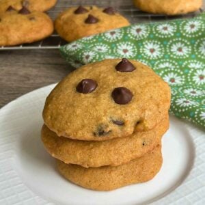A stack of three banana chocolate chip cookies on a white plate.