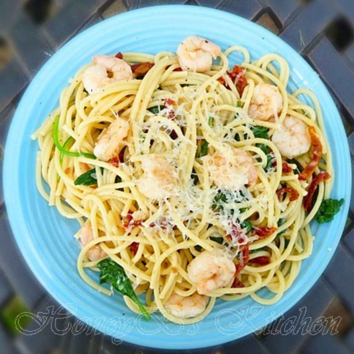 A healthy serving of shrimp and spinach vermicelli with a light garlic butter sauce and sun-dried tomato pieces.