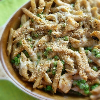 A casserole dish with pasta, chicken, and green peas with a breadcrumb topping.