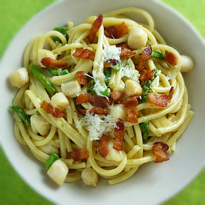 Overhead view of Scallop and Asparagus Carbonara with bacon and paremsan cheese.