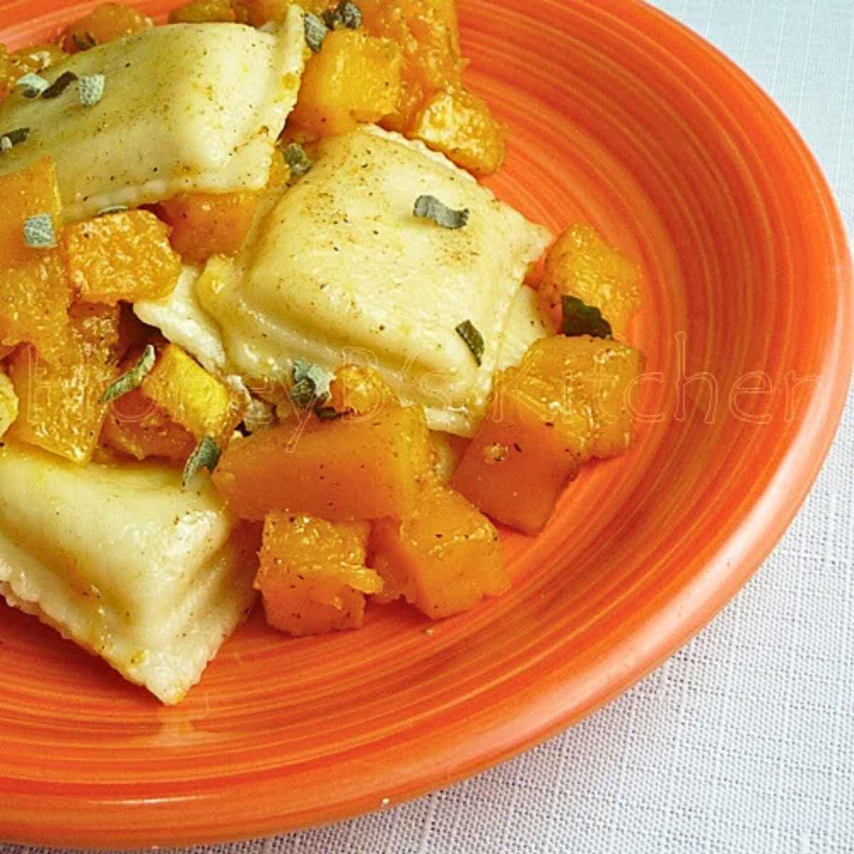 Upclose image of Butternut Squash Ravioli with sage browned butter on an orange plate.