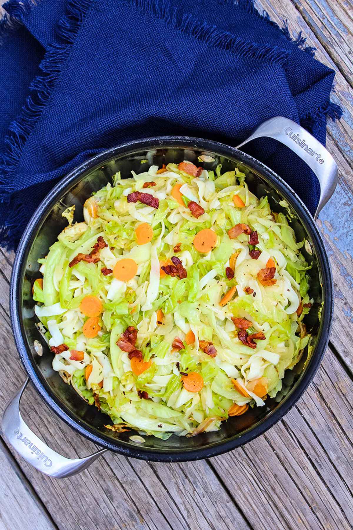 Overhead view of sauteed vegetables and bacon being prepared in a black skillet.