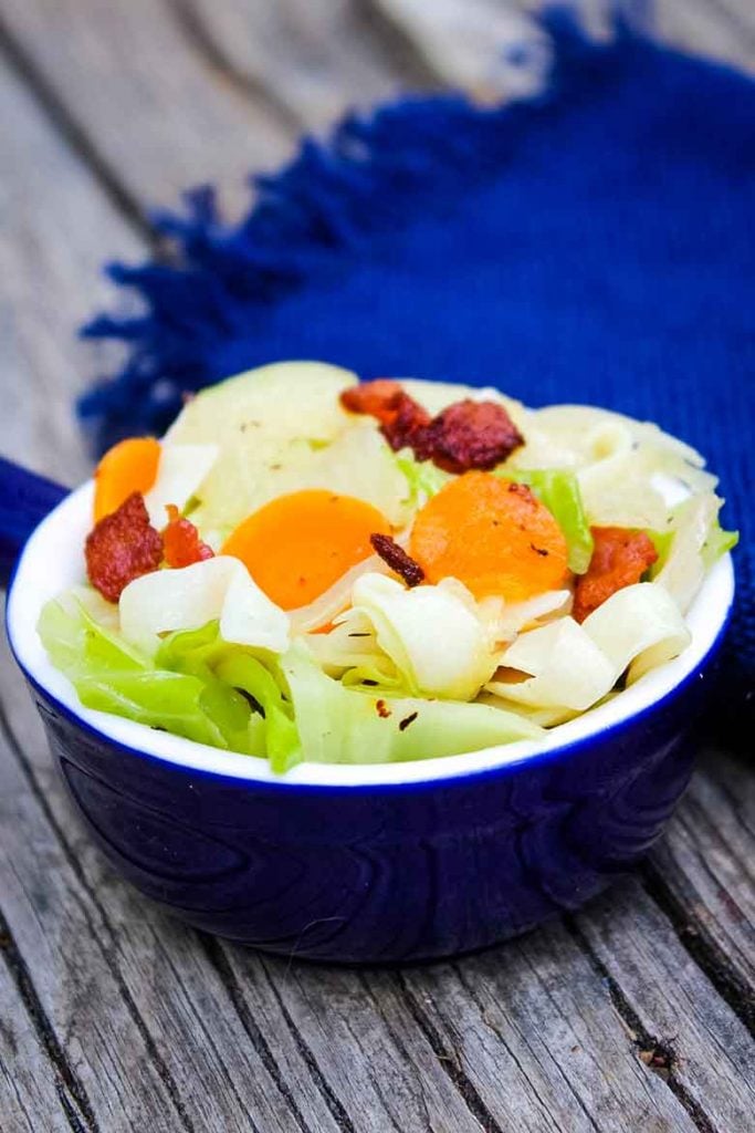 Cabbage Noodles with Bacon in a blue serving bowl with a blue napkin in the background