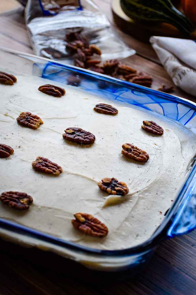 Banana Cake with Maple Frosting decorated with pecans in a blue cake pan.