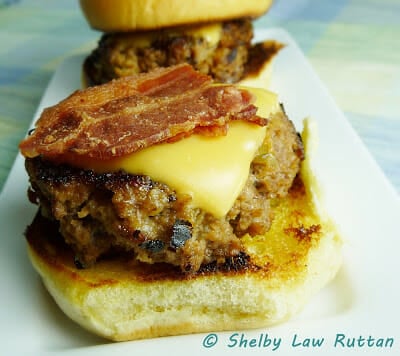 slider on bottom half of toasted bun with bacon and cheese on top of burger