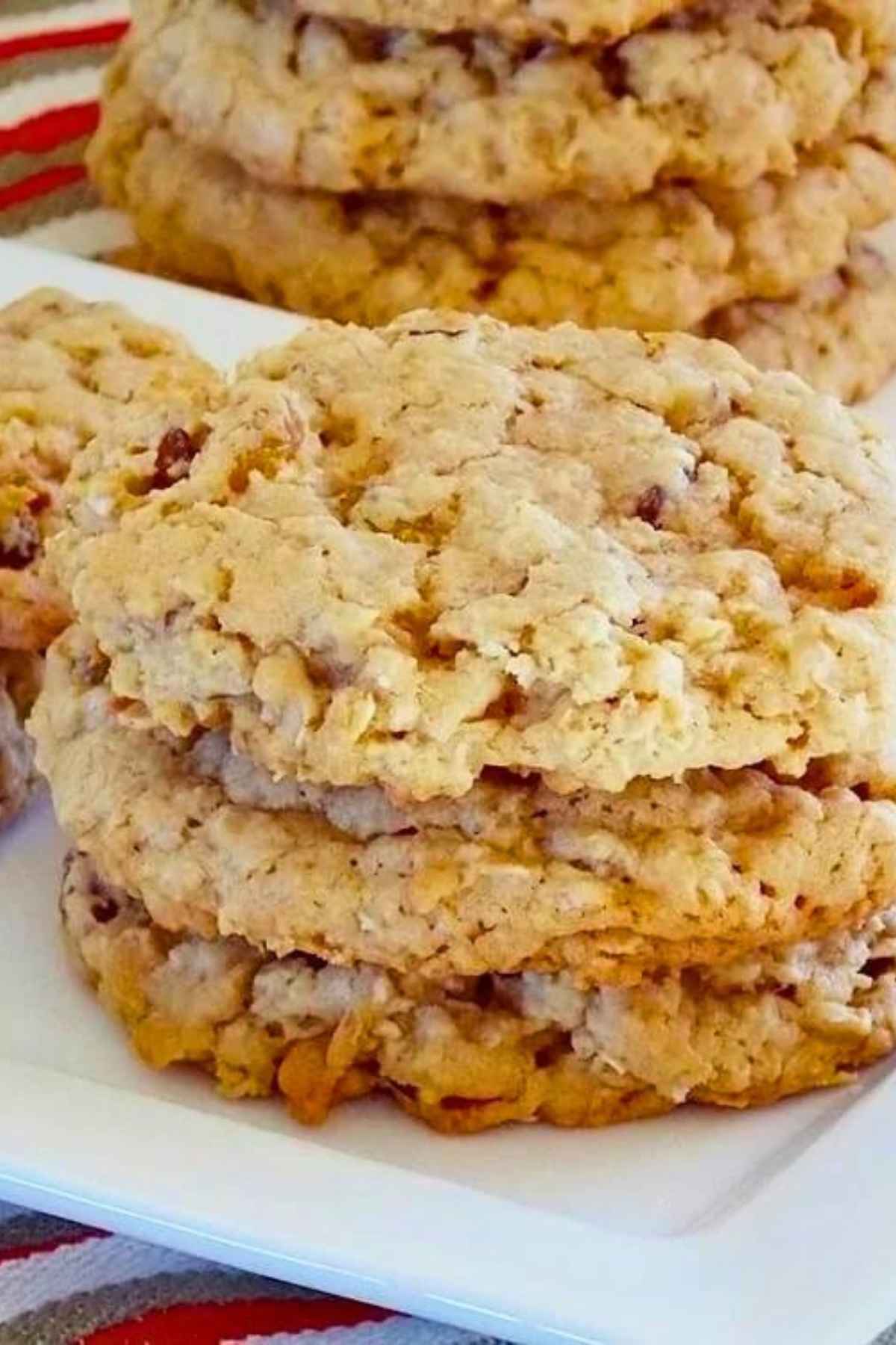 A stack of three vanishing oatmeal cookies on a white plate with more cookies in the background.