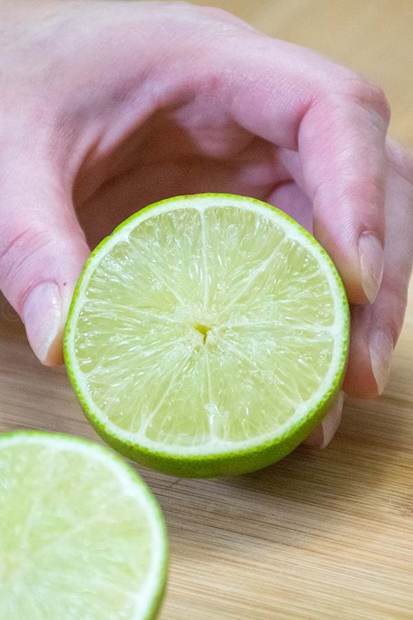 a hand holding ½ of a cut lime