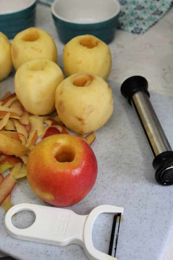 Peeled and cored apples with an apple peeler and corer next to them.