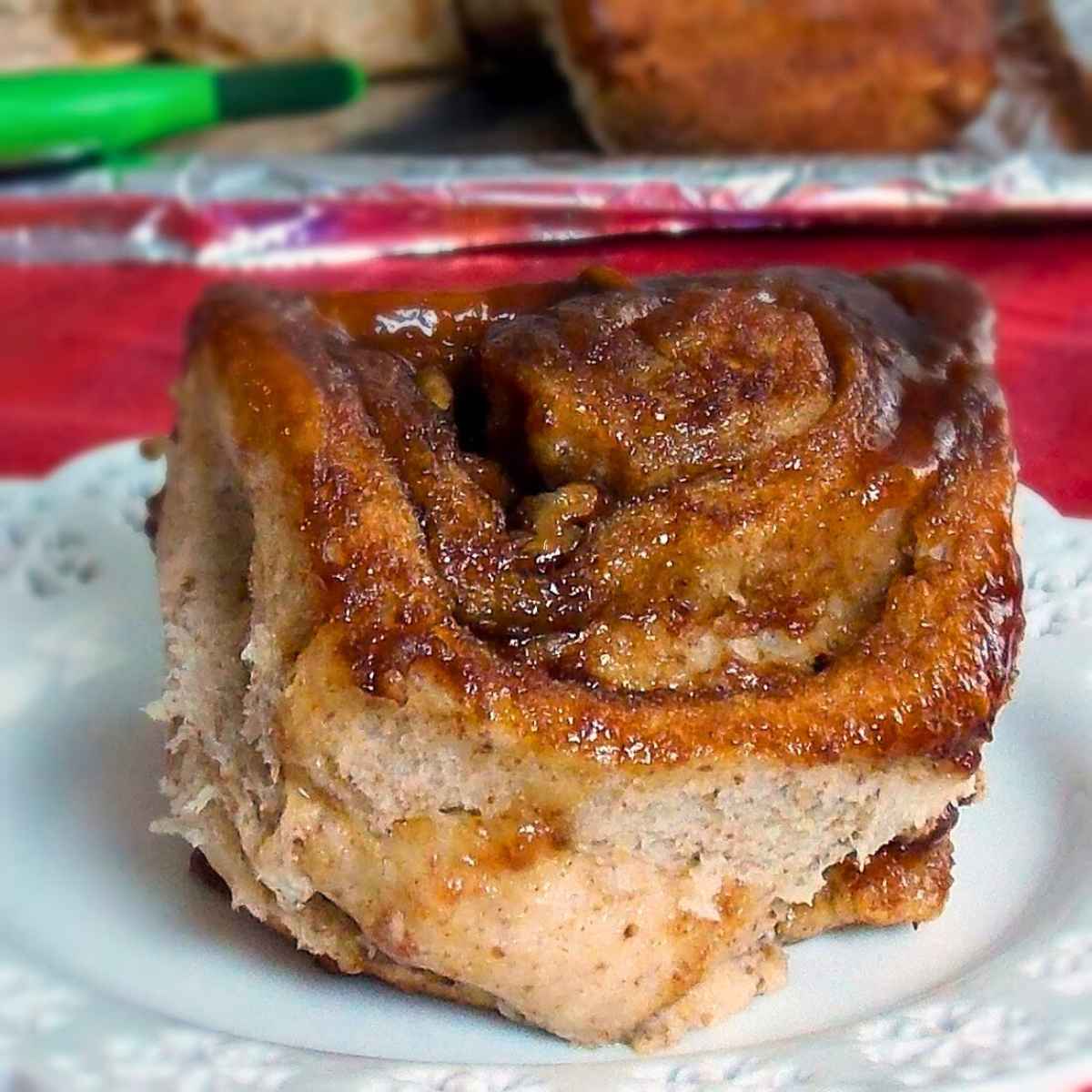 Close up of a sticky apple butter cinnamon roll on a white plate, showing its soft layers and caramelized glaze.