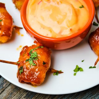 Bacon Wrapped Water Chestnuts with dipping sauce sprinkled with fresh cilantro