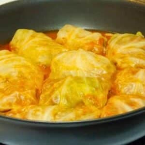 Stovetop venison cabbage rolls simmering in a skillet with tangy tomato sauce.