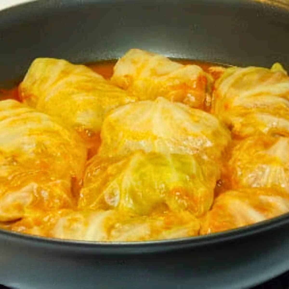 Stovetop venison cabbage rolls simmering in a skillet with tangy tomato sauce.