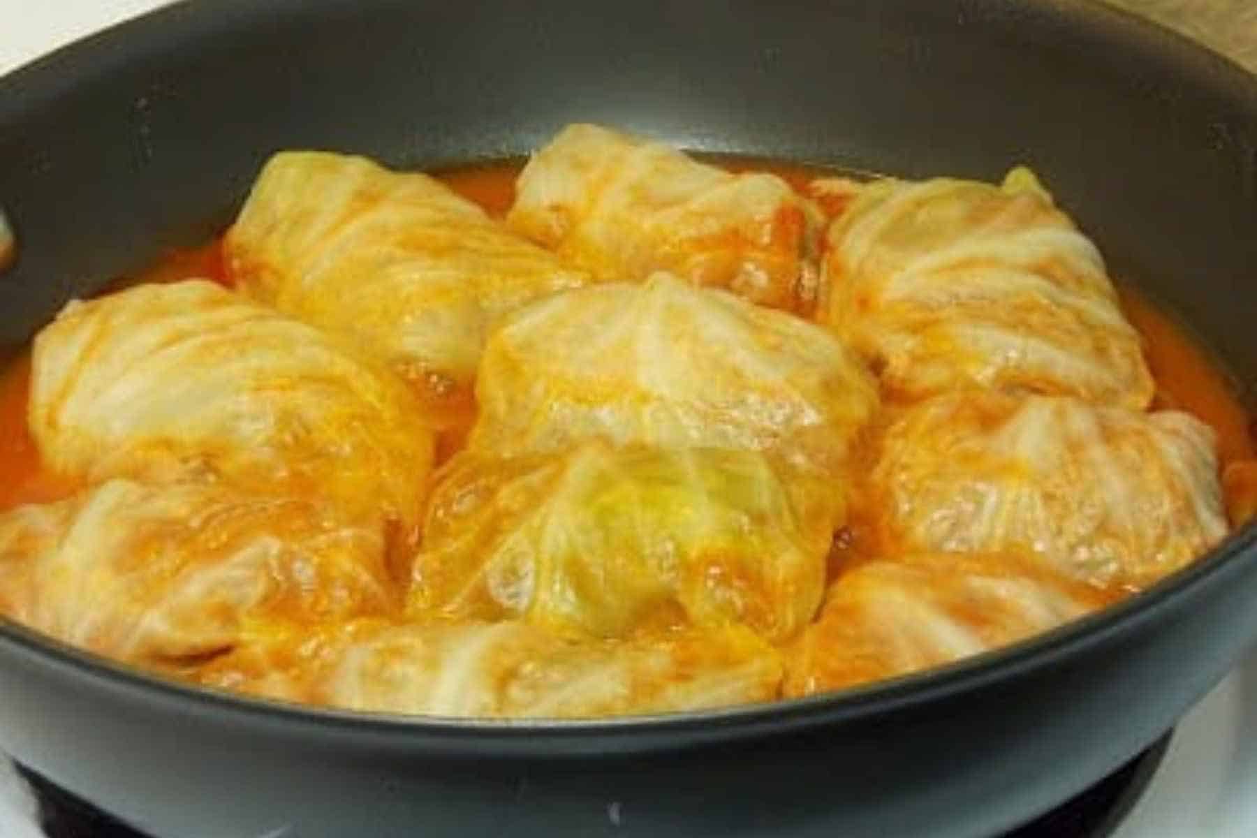 Stovetop venison cabbage rolls simmering in a skillet with tangy tomato sauce.