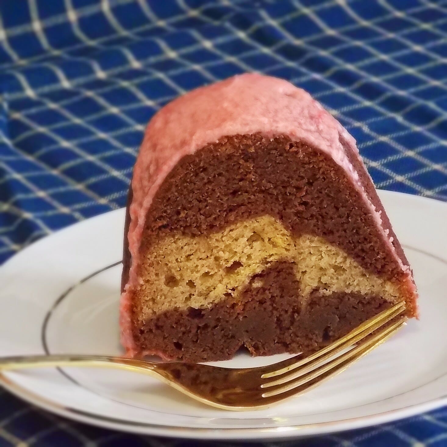 One slice chocolate marbled banana bundt cake with strawberry icing.