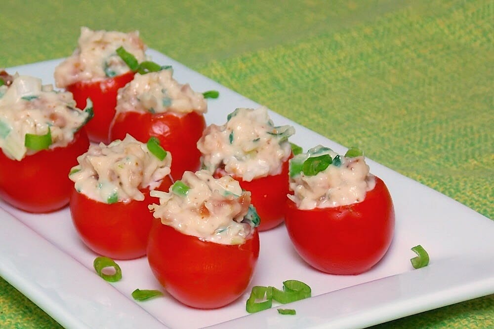 Stuffed tomatoes on a white plate with parsley garnish.