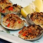 A white plate with Stuffed Clams with Pancetta and lime wedge garnish.