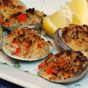 A white plate with Stuffed Clams with Pancetta and lime wedge garnish.