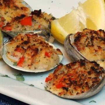 A white plate with Stuffed Clams with Pancetta and lime wedge garnish.