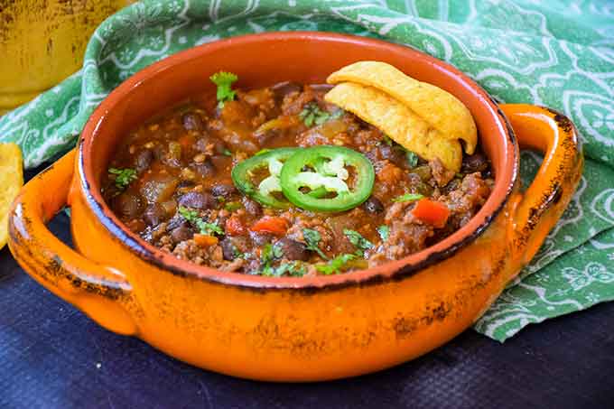 Black Bean Chili in an orange bowl with a green napkin next to it