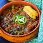 Mexican Black Bean Chili in an orange bowl topped with jalapeno slices and corn chips.