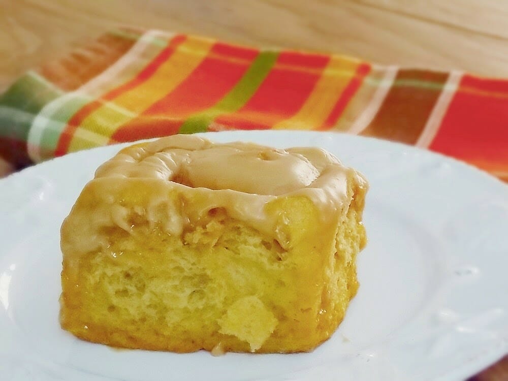 Pumpkin cookie butter cinnamon roll on a white plate.