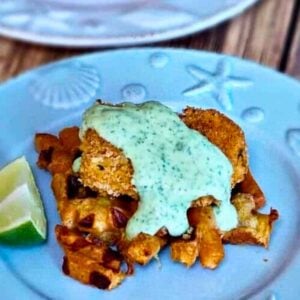 Chicken and Sweet Potato Waffles with Cilantro Lime Sauce on a blue plate with a lime wedge garnish.