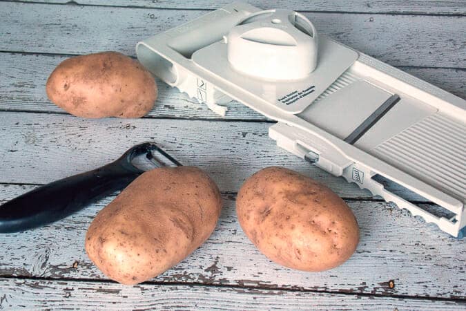 3 potatoes, a potato peeler, and mandolin