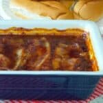 Blue casserole dish filled with bourbon bacon topped baked beans.