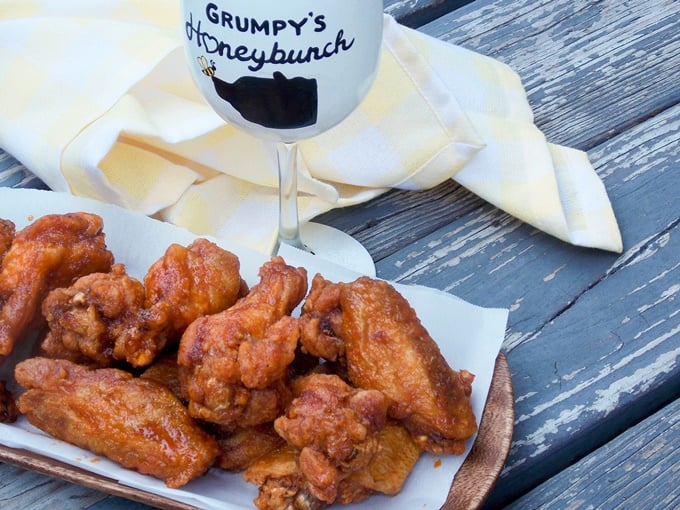 Fried wings on a serving tray with a wine glass in the background