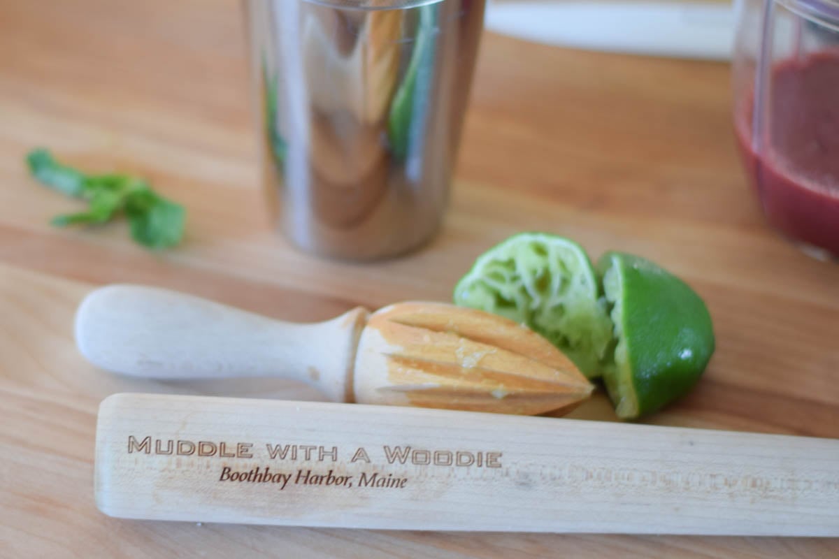 a juice reamer, muddler, limes, and cocktail shaker