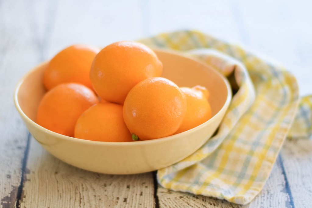 a yellow bowl filled with meyer lemons on a blue and yellow checked towel