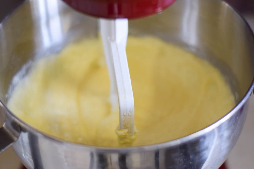 Cake batter being mixed in a red kitchenaid mixer