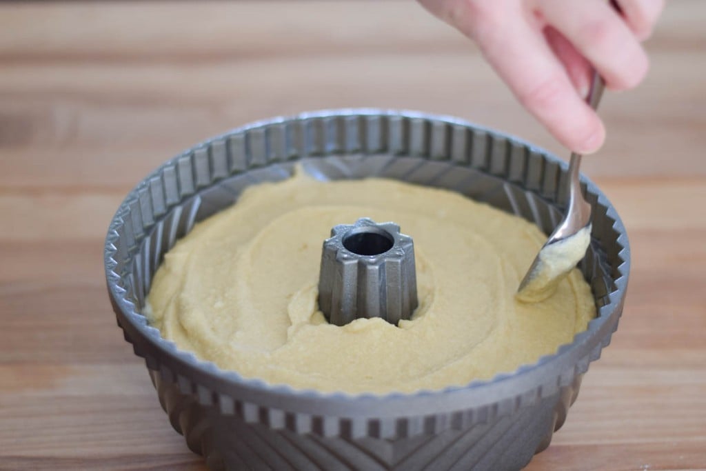 Smoothing the cake batter into the bundt pan with a spoon