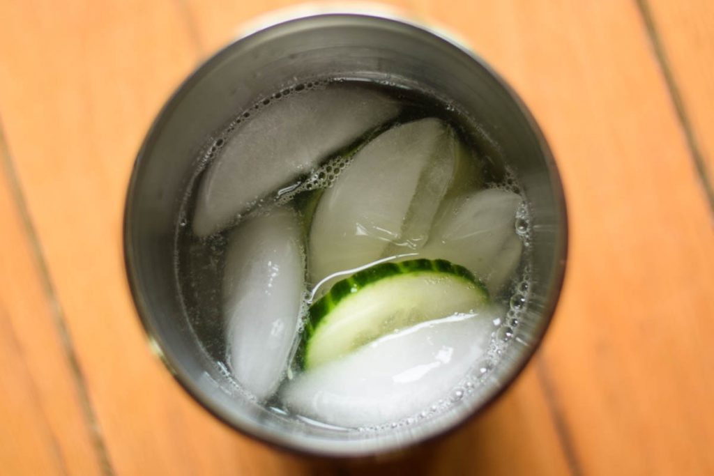 Cucumbers ice and lemon lime rum collins in a cocktail shaker