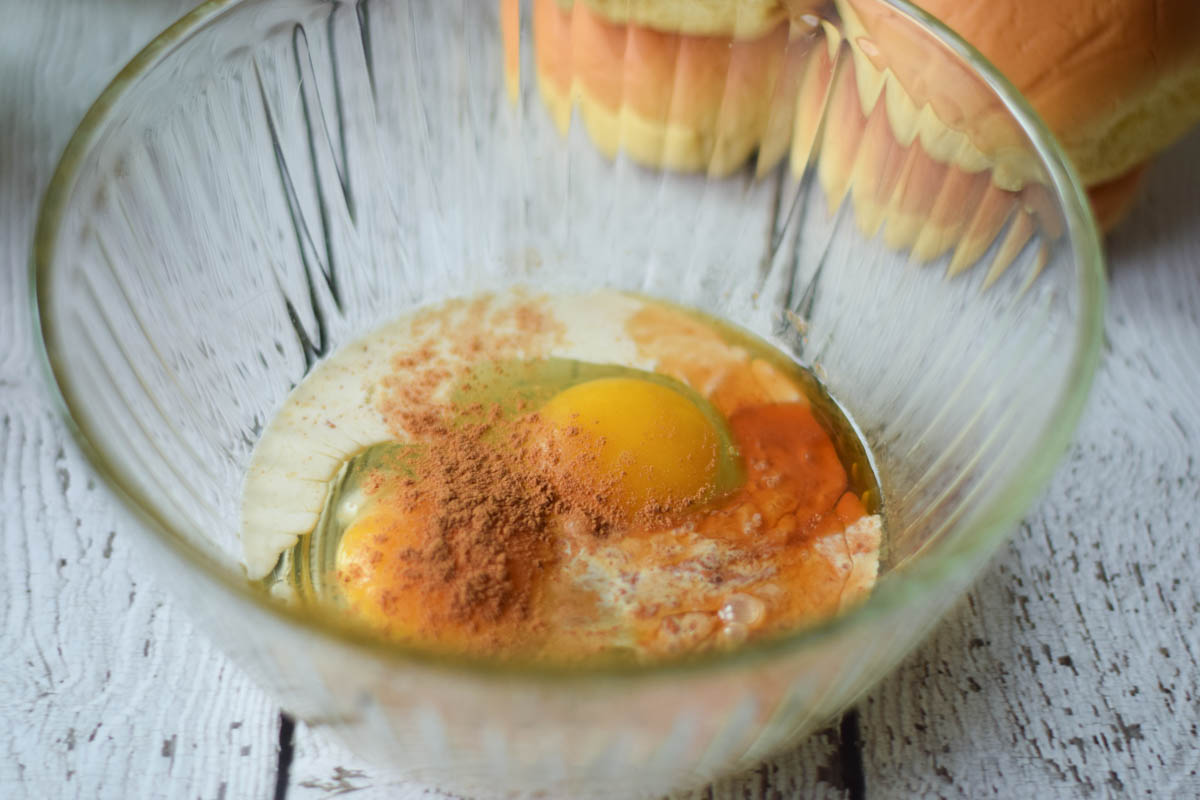 Eggs, vanilla, cream, and ground cinnamon in a mixing bowl.