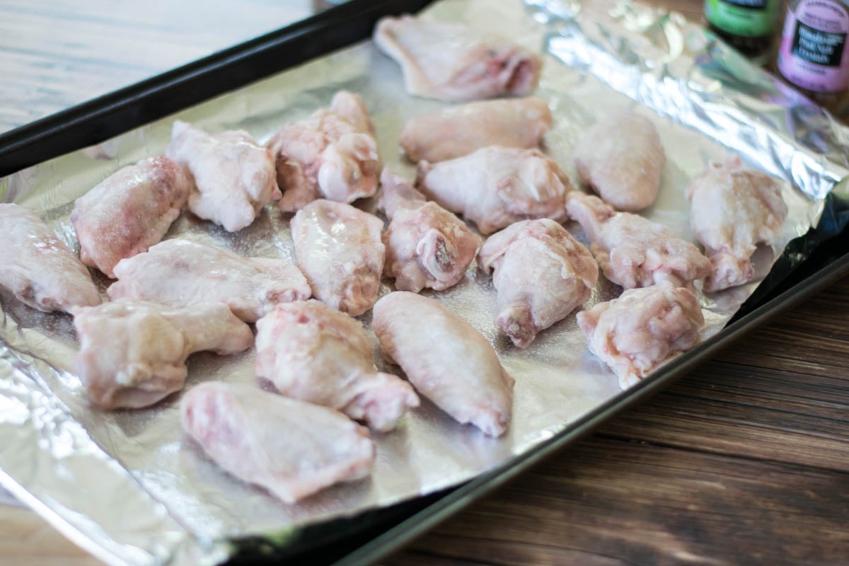 Frozen chicken portions on a baking tray covered with aluminum foil.