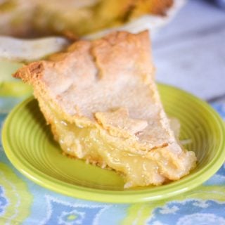 A slice of pineapple pie on a neon green plate with the whole pie dish in the background