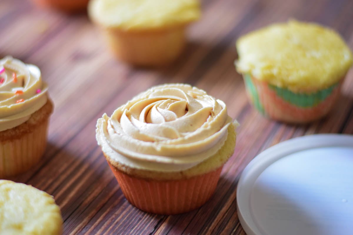 A single frosted cupcake with unfrosted cupcakes in the background.