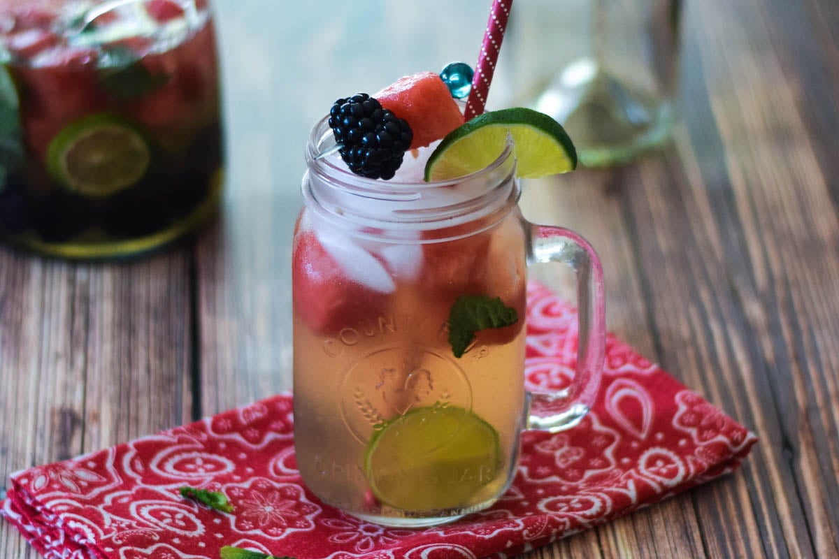 A wine sangria with watermelon, blackberries, and lemon slices in a mason drinking jar.