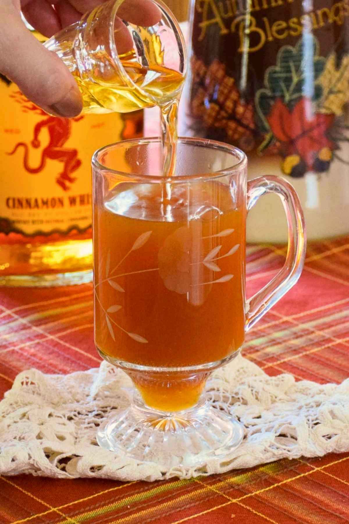 Pouring a shot of fireball whisky into the hot apple cider.
