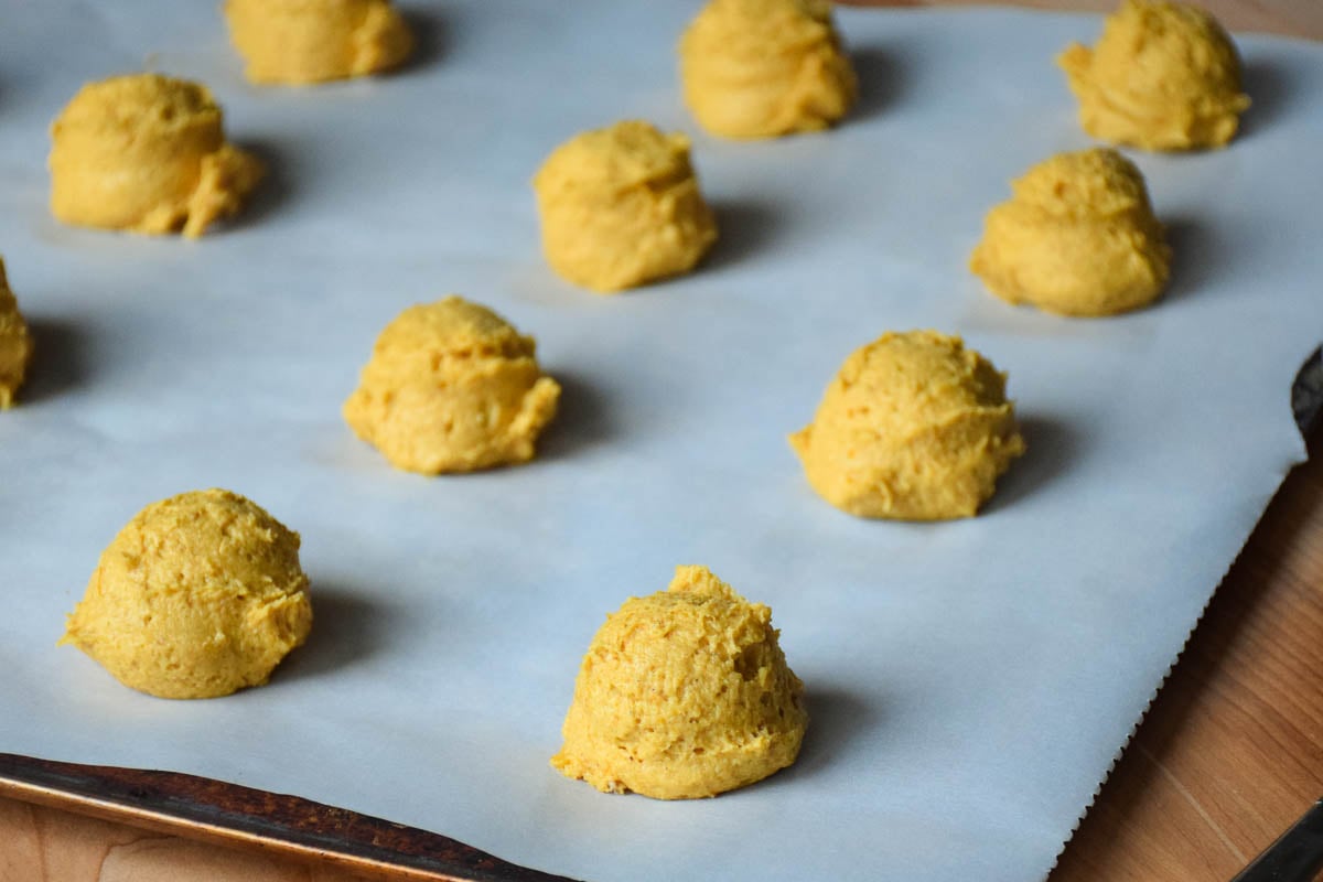 Portioned cookie dough on a parchment lined cookie sheet.